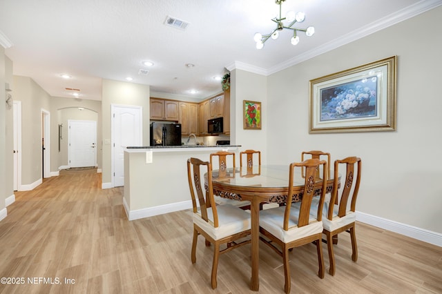 dining space with a notable chandelier, ornamental molding, and light hardwood / wood-style floors