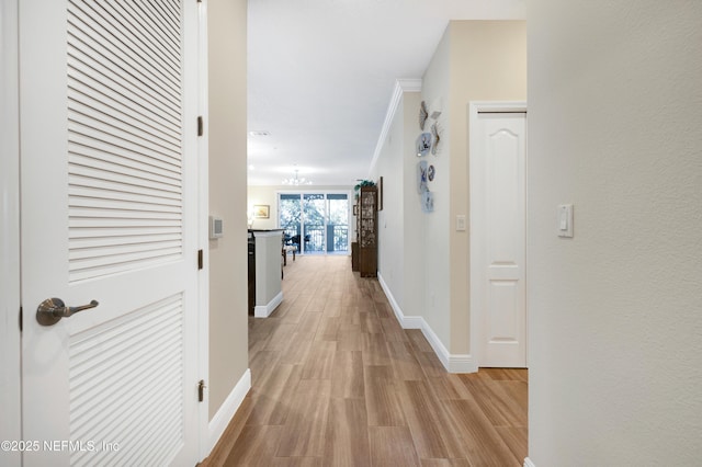 hallway featuring crown molding, an inviting chandelier, and light hardwood / wood-style flooring