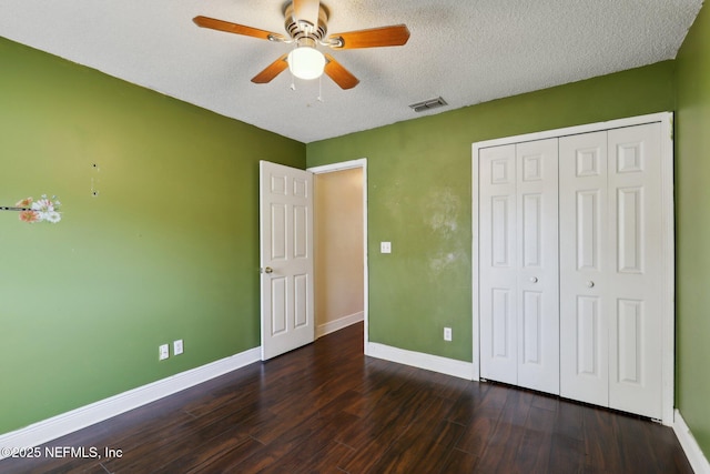 unfurnished bedroom featuring ceiling fan, dark hardwood / wood-style floors, a closet, and a textured ceiling