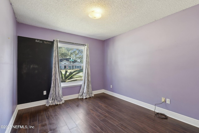 empty room with dark hardwood / wood-style flooring and a textured ceiling