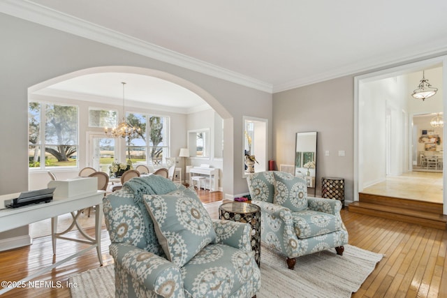 living room with ornamental molding, a chandelier, and light wood-type flooring