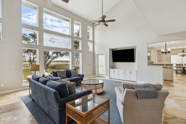 living room featuring ceiling fan with notable chandelier and a high ceiling