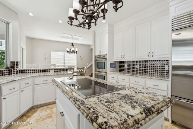 kitchen with white cabinetry, stainless steel appliances, a center island, and a chandelier