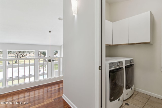 laundry area featuring cabinets, washer and clothes dryer, and tile patterned flooring