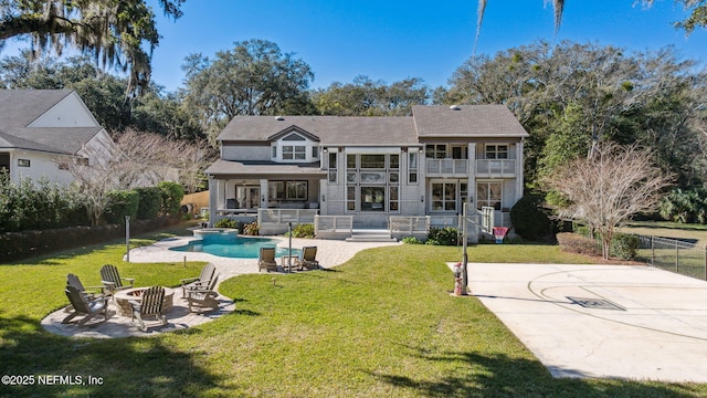 rear view of house featuring a patio, a balcony, a yard, and a fire pit