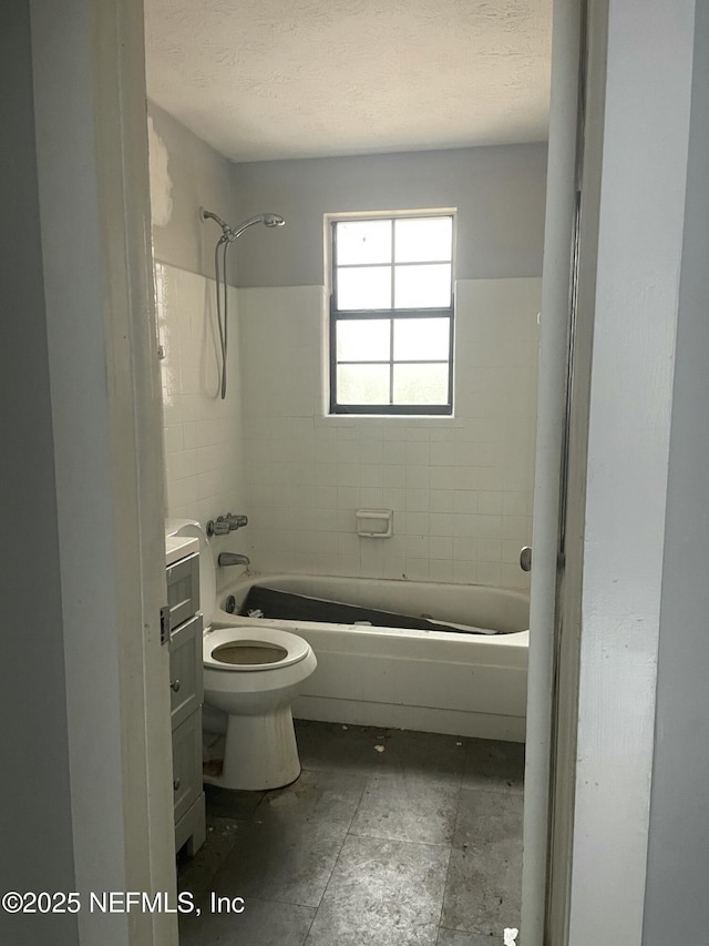 full bathroom featuring tiled shower / bath, vanity, toilet, and a textured ceiling