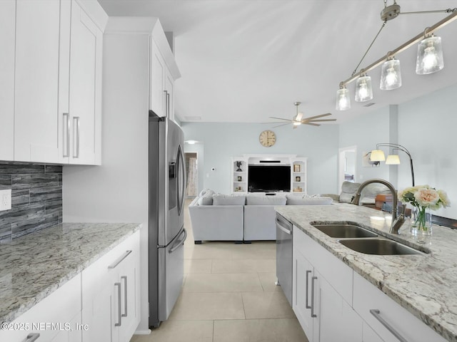 kitchen with sink, light tile patterned floors, stainless steel appliances, light stone counters, and white cabinets