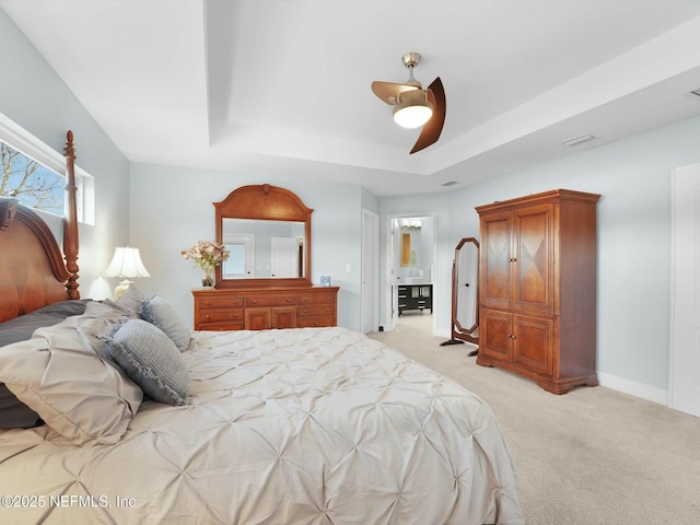 bedroom featuring light carpet, a tray ceiling, and ceiling fan