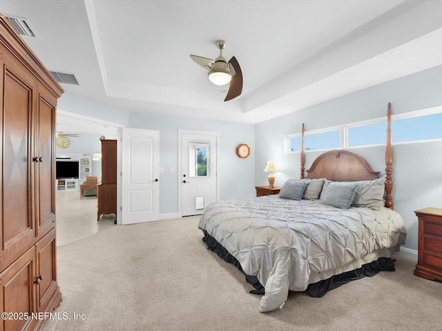 carpeted bedroom featuring ceiling fan and a tray ceiling