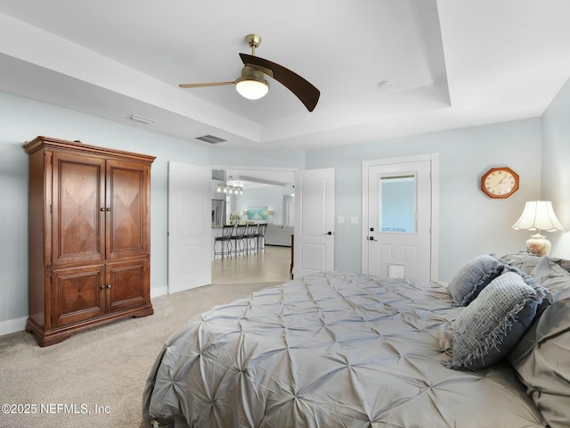 bedroom featuring a raised ceiling, light colored carpet, and ceiling fan