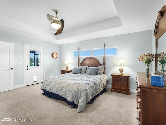 carpeted bedroom featuring a raised ceiling and ceiling fan