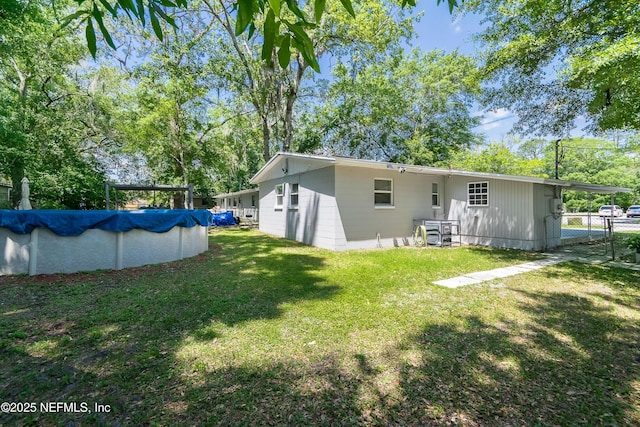 back of property featuring a covered pool and a lawn