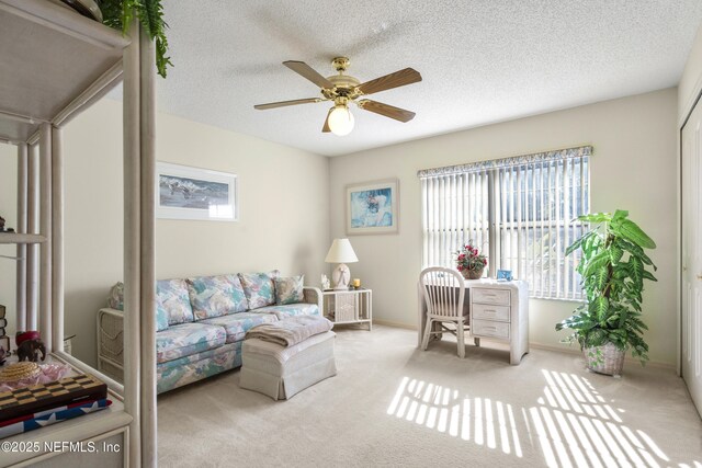 living room featuring ceiling fan, light carpet, a wealth of natural light, and a textured ceiling