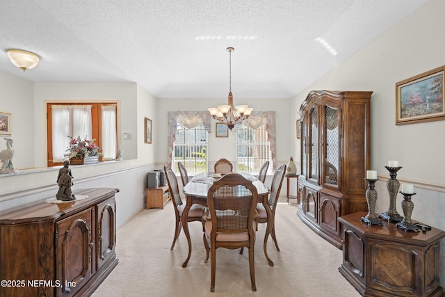 dining room featuring an inviting chandelier, light carpet, and a textured ceiling