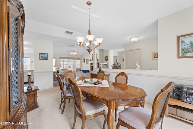 carpeted dining room with vaulted ceiling and ceiling fan with notable chandelier