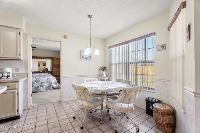 tiled dining space featuring a notable chandelier and a textured ceiling