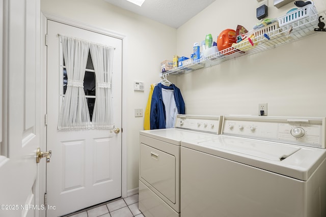 laundry room featuring light tile patterned floors, washing machine and dryer, and a textured ceiling