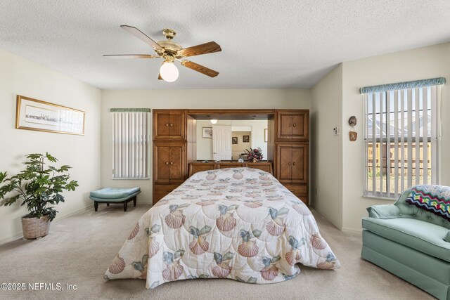 carpeted bedroom featuring ceiling fan and a textured ceiling