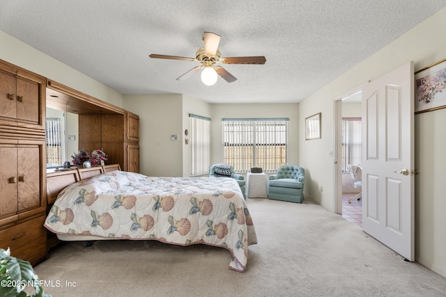 bedroom with light carpet, ceiling fan, and a textured ceiling