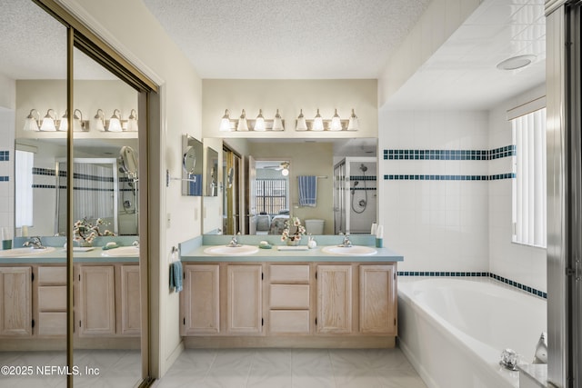 bathroom featuring ceiling fan, vanity, independent shower and bath, and a textured ceiling