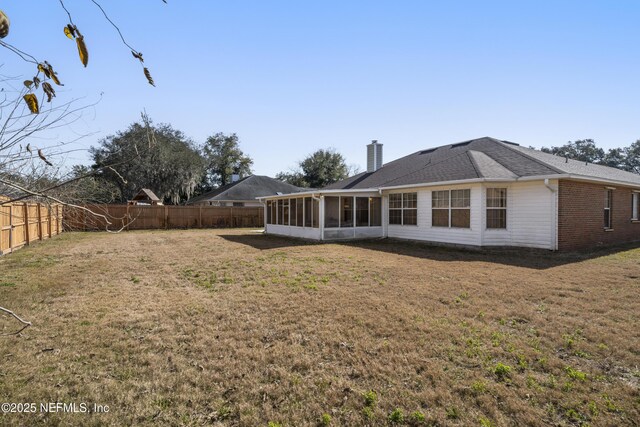 rear view of property with a yard and a sunroom