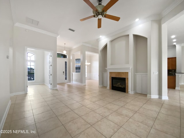 unfurnished living room with a tiled fireplace, ornamental molding, ceiling fan with notable chandelier, and light tile patterned floors