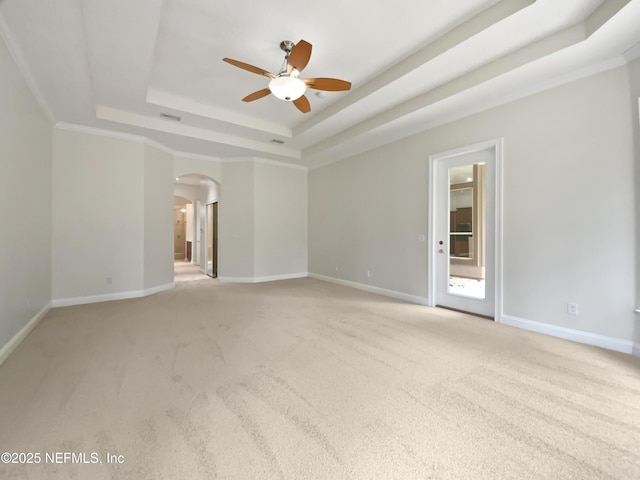 unfurnished room with a raised ceiling, ornamental molding, light carpet, and ceiling fan