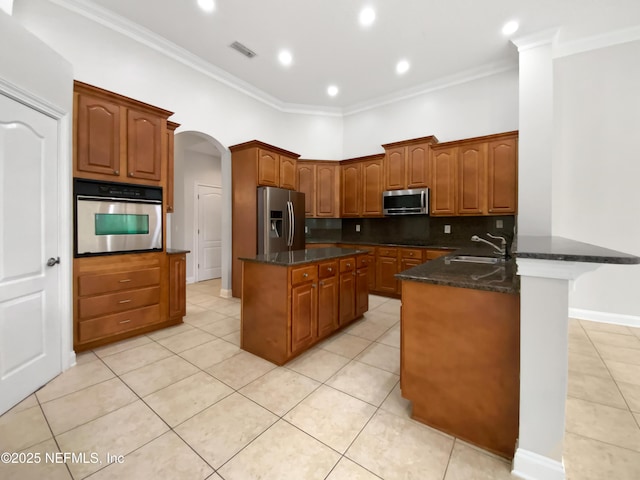 kitchen with dark stone countertops, sink, crown molding, and stainless steel appliances