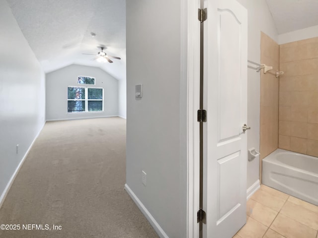 interior space with ceiling fan, a textured ceiling, bathtub / shower combination, vaulted ceiling, and tile patterned floors