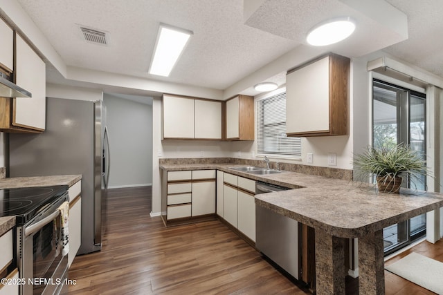 kitchen featuring sink, white cabinets, kitchen peninsula, stainless steel appliances, and a textured ceiling