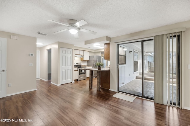 unfurnished living room featuring ceiling fan, plenty of natural light, dark hardwood / wood-style flooring, and a textured ceiling