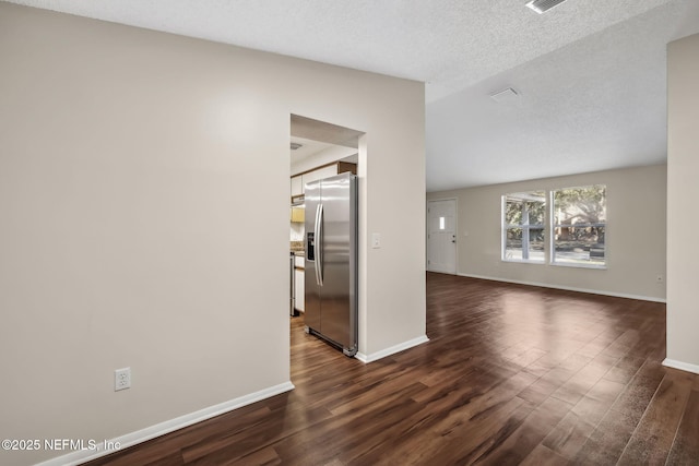 empty room with dark wood-type flooring and a textured ceiling