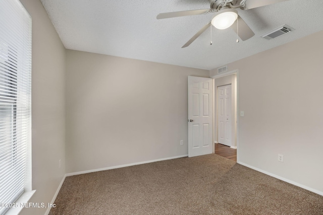 unfurnished bedroom featuring dark colored carpet, a textured ceiling, and ceiling fan