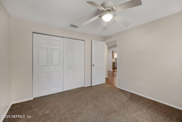 unfurnished bedroom with a textured ceiling, a closet, ceiling fan, and carpet flooring