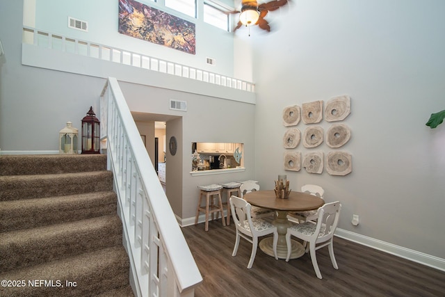 dining room featuring a high ceiling, ceiling fan, and dark hardwood / wood-style flooring