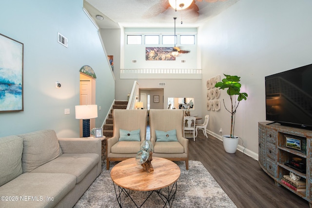 living room featuring ceiling fan, wood-type flooring, and a high ceiling