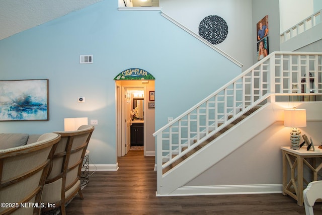 staircase featuring wood-type flooring and a high ceiling