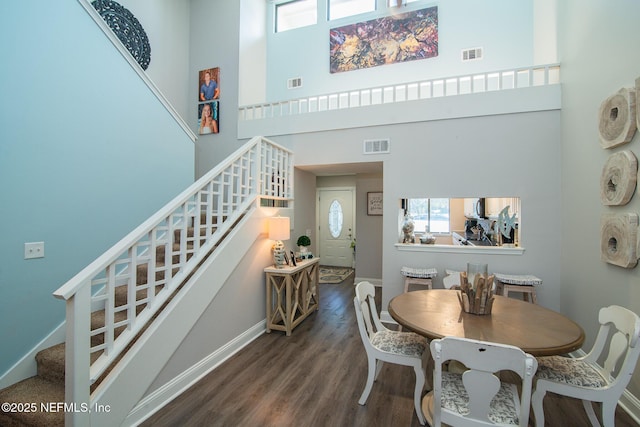 dining space featuring a towering ceiling and dark hardwood / wood-style floors