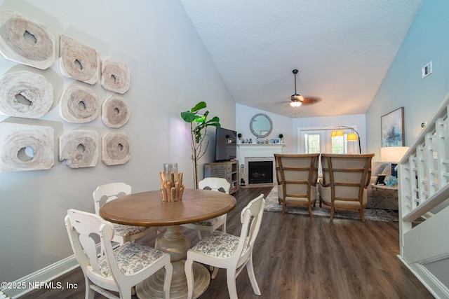 dining area featuring a textured ceiling, dark wood-type flooring, ceiling fan, and vaulted ceiling