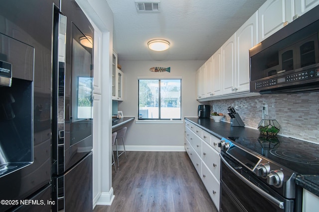 kitchen with white cabinetry, double oven range, backsplash, wood-type flooring, and a textured ceiling