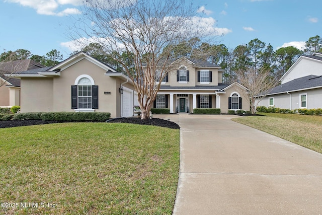 traditional-style home with driveway, an attached garage, a front lawn, and stucco siding