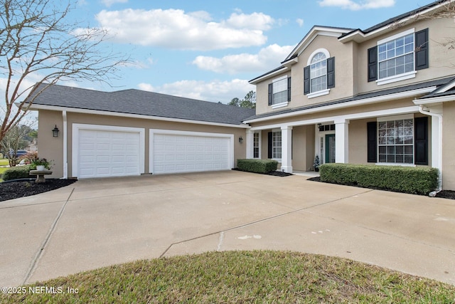 traditional-style house featuring concrete driveway, an attached garage, and stucco siding