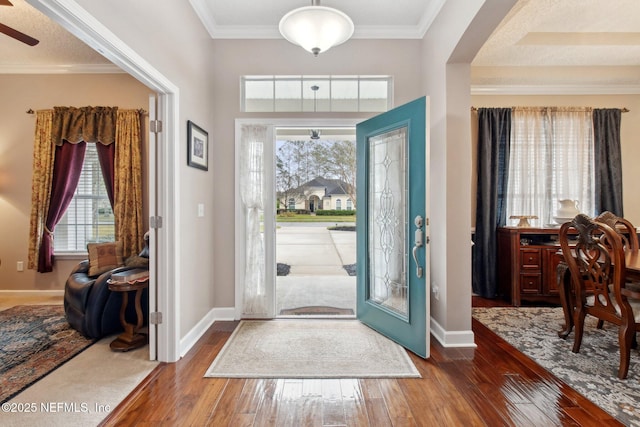 entrance foyer with baseboards, arched walkways, a ceiling fan, hardwood / wood-style flooring, and crown molding