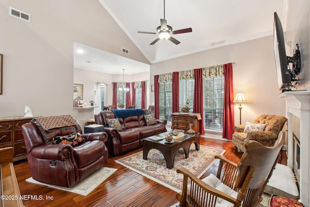 living area featuring ceiling fan with notable chandelier, visible vents, a fireplace, and wood finished floors