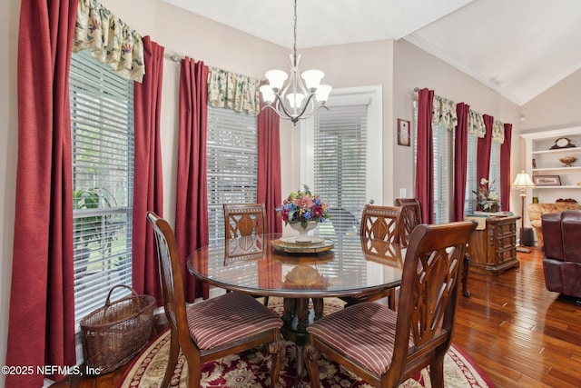 dining space featuring crown molding, a notable chandelier, vaulted ceiling, and wood finished floors