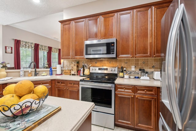 kitchen featuring appliances with stainless steel finishes, light countertops, a sink, and backsplash