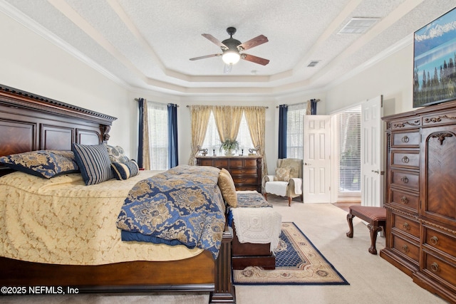 carpeted bedroom featuring a textured ceiling, ceiling fan, visible vents, ornamental molding, and a raised ceiling