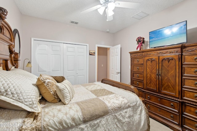 carpeted bedroom with a textured ceiling, ceiling fan, a closet, and visible vents