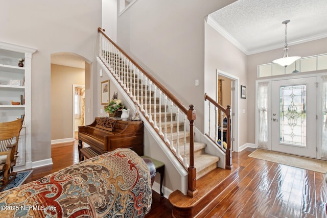 entrance foyer featuring arched walkways, baseboards, crown molding, and hardwood / wood-style floors