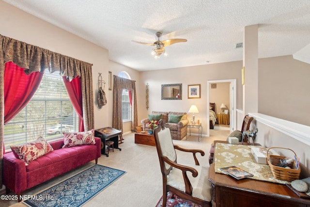 living area with light carpet, ceiling fan, visible vents, and a textured ceiling